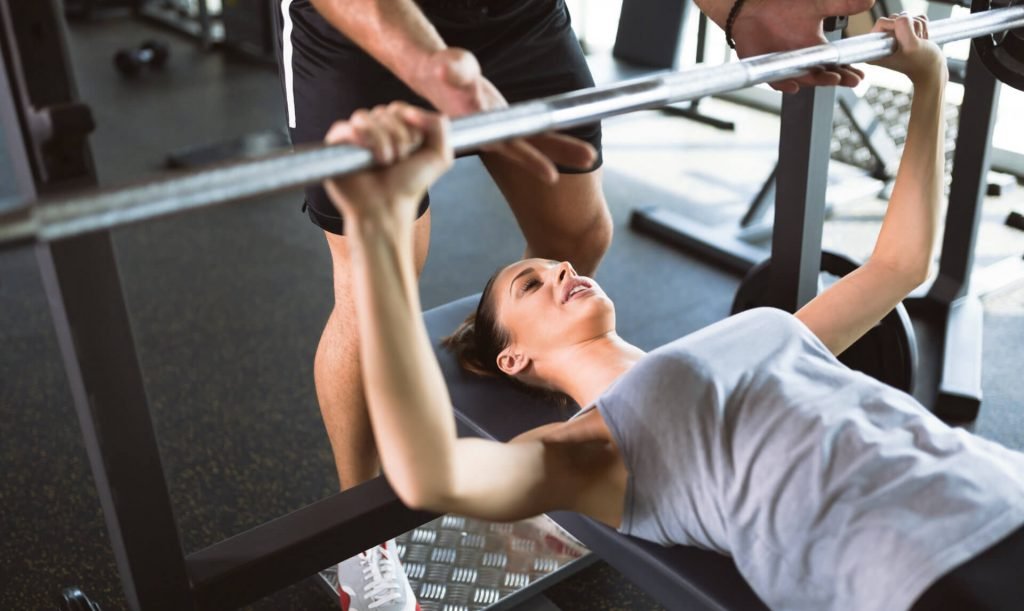 personal trainer assisting woman